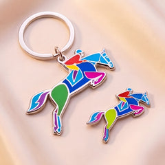 Colorful horse-shaped enamel keychain and pin on a soft beige background by Spot Studio Art.