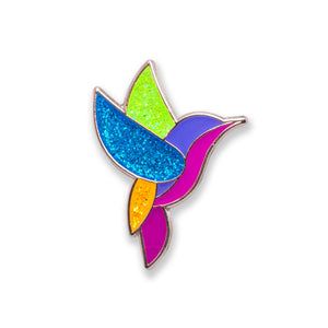 A colorful enamel pin shaped like a hummingbird with silver plating and glitter inlay.