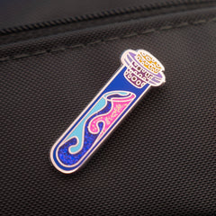 Colorful magic potion vial glittery enamel pin on a black bag.
