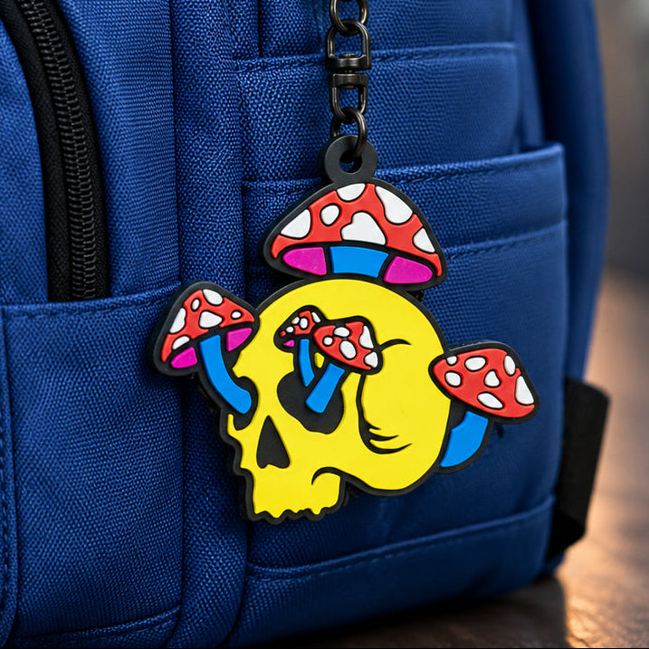 Colorful mushroom skull charm attached to a blue backpack on a wooden surface.