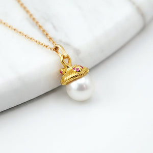 Gold necklace with a pearl pendant on a white surface