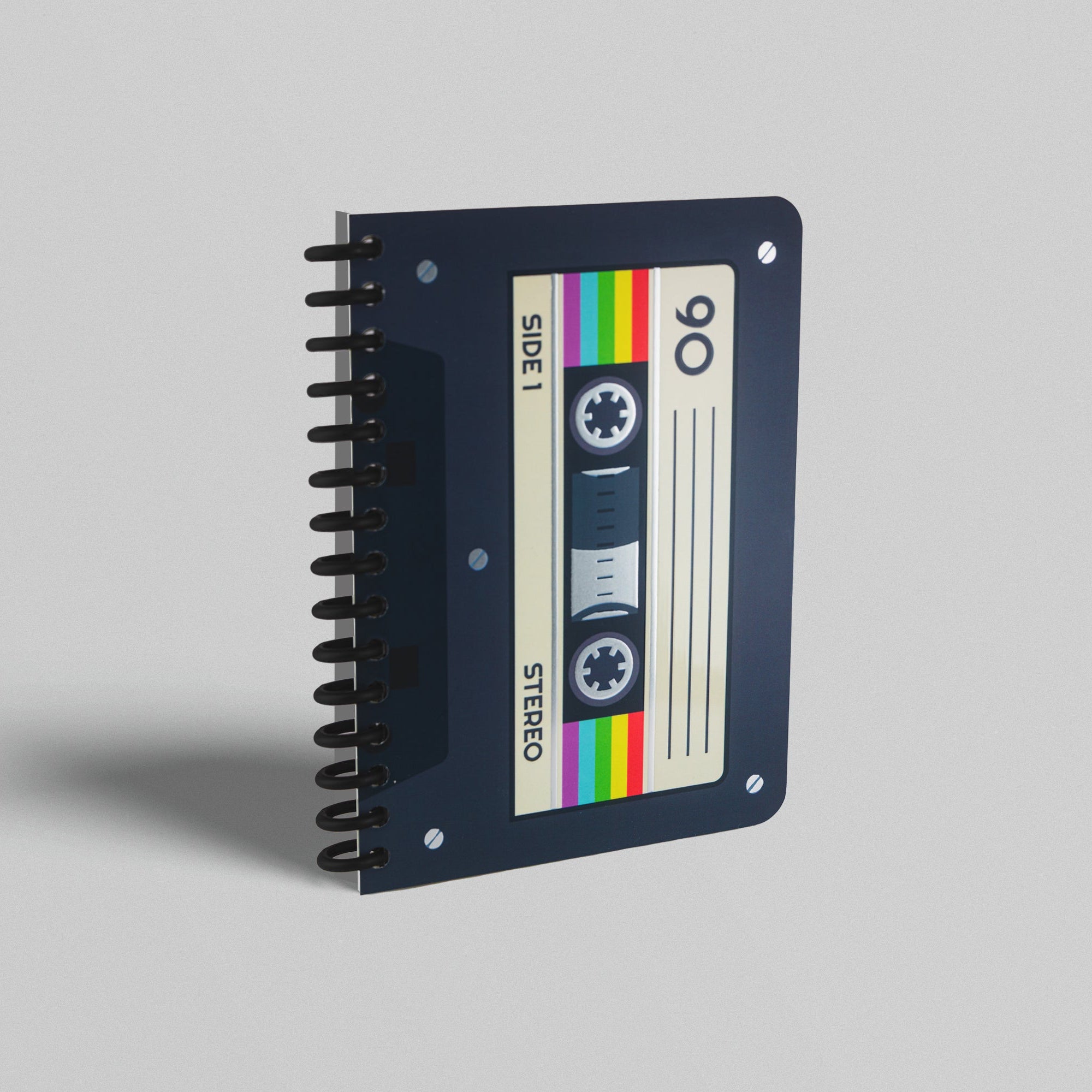 A notebook with a cassette tape design on its cover, featuring silver foiled accents and a colorful striped pattern.