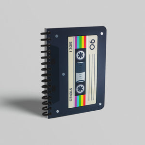 A notebook with a cassette tape design on its cover, featuring silver foiled accents and a colorful striped pattern.
