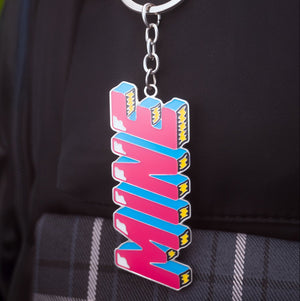 Colorful 'MINE' keychain attached to a black backpack
