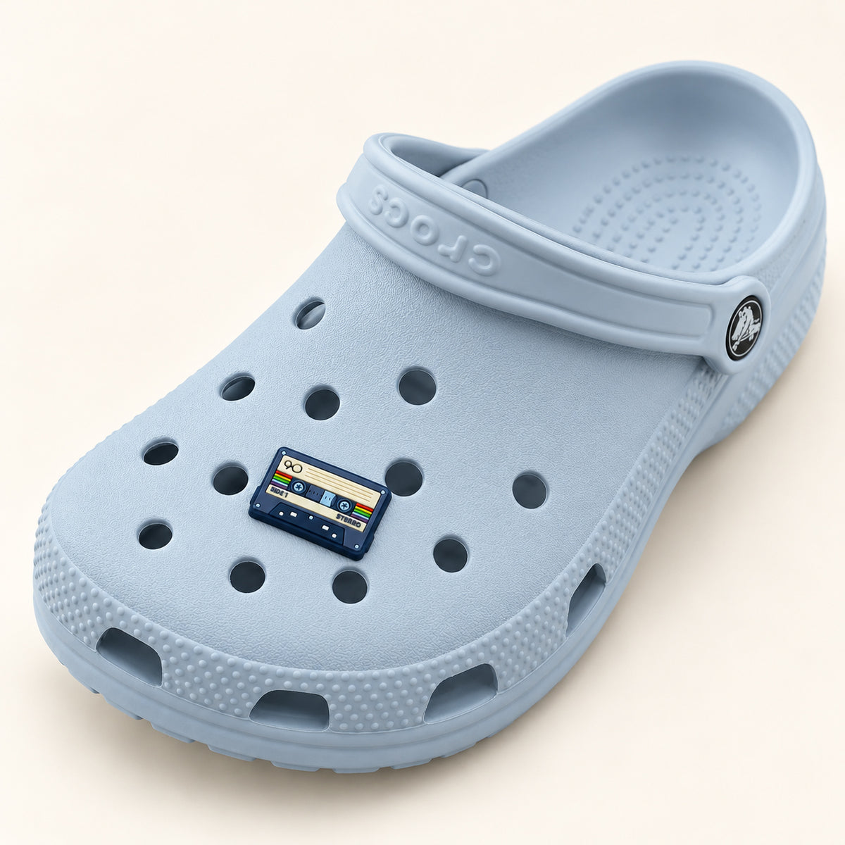 Full powder-blue Croc displaying one small retro cassette tape shoe charm; shoe is shown for styling only.