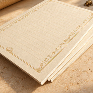 Close-up of lined Egyptian 4 by 6 inch notepads with gold hieroglyph-inspired borders and a lotus motif on a cream background