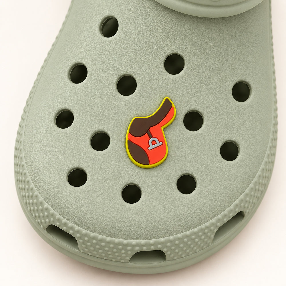 Overhead view of the 1.25-inch English saddle shoe charm on a sage-green Croc.