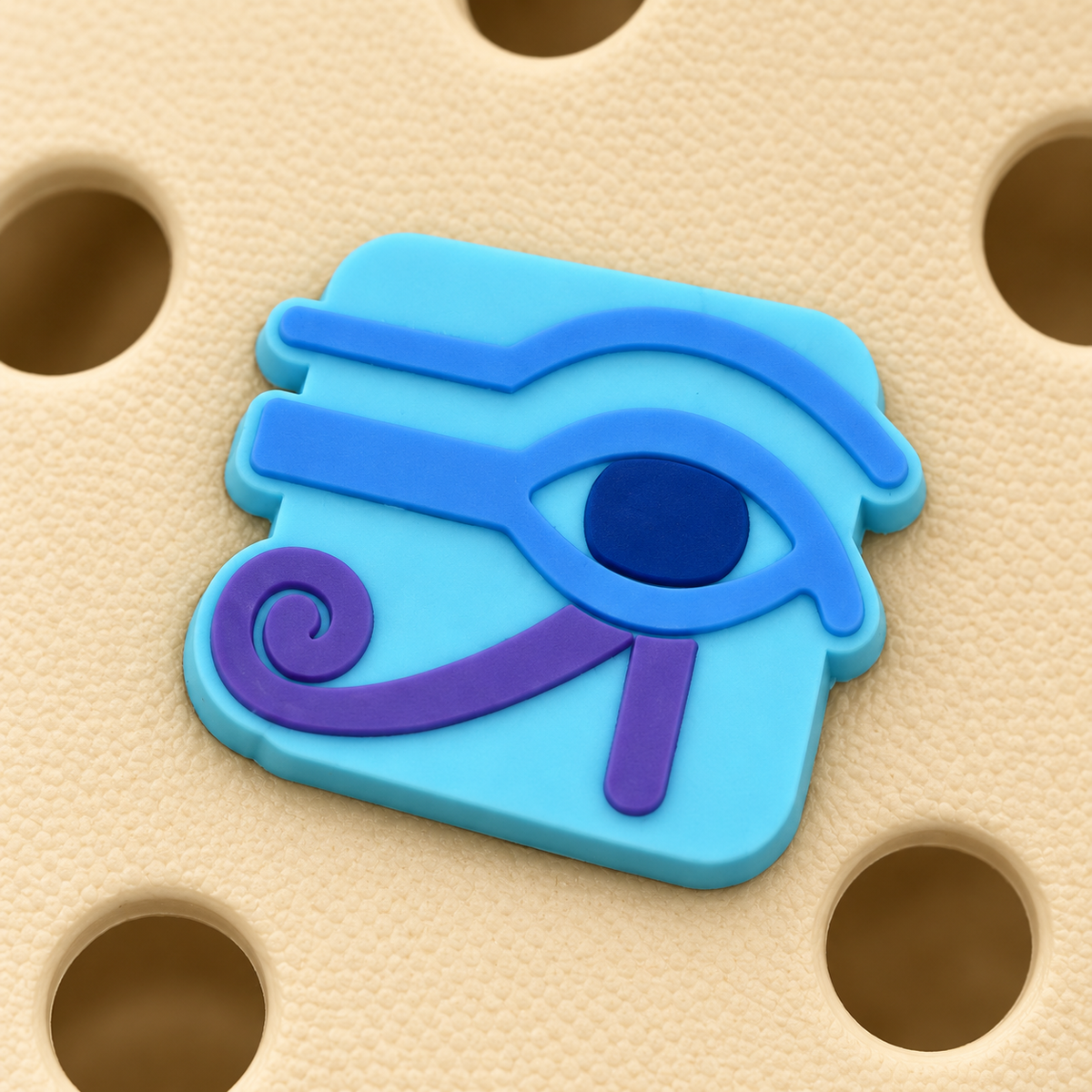 Macro close-up of the Eye of Horus charm showing its turquoise backing, raised blue eye, dark-blue pupil, and purple flourish.